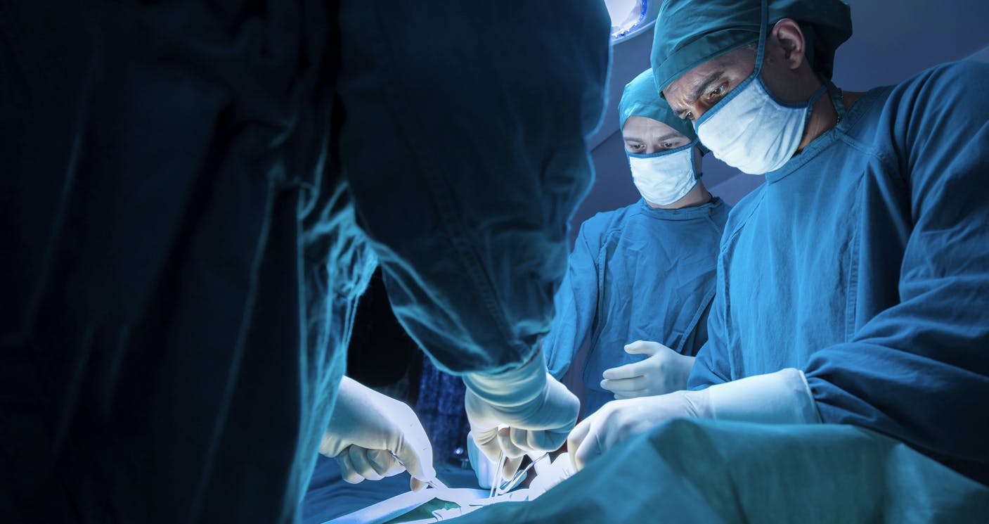 plastic surgeons standing over a patient stock image